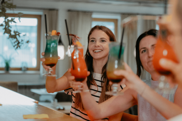 Gäste stoßen mit bunten Cocktails in geselliger Runde an