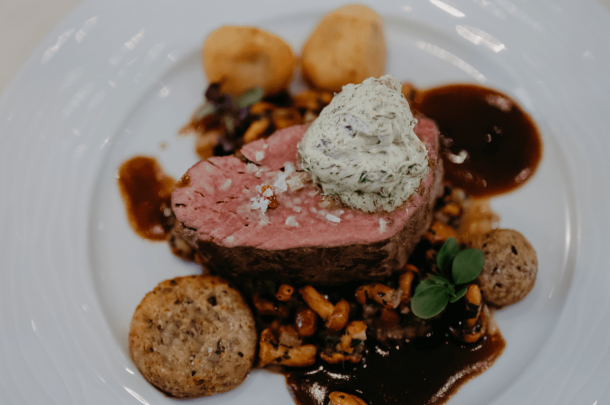 Gourmetgericht mit Rindfleisch, Gemüse und Knödeln auf edlem Porzellan